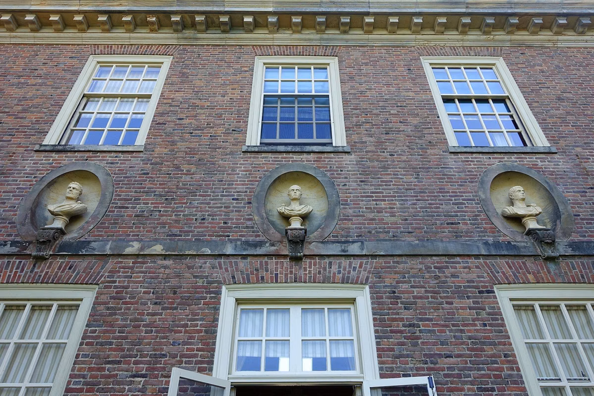 Brick facade of the Great House with carved busts in round niches below the windows