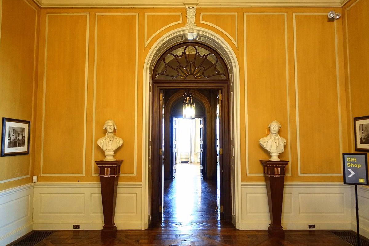The Gallery inside the Great House, with busts on pedestals either side of an arched doorway