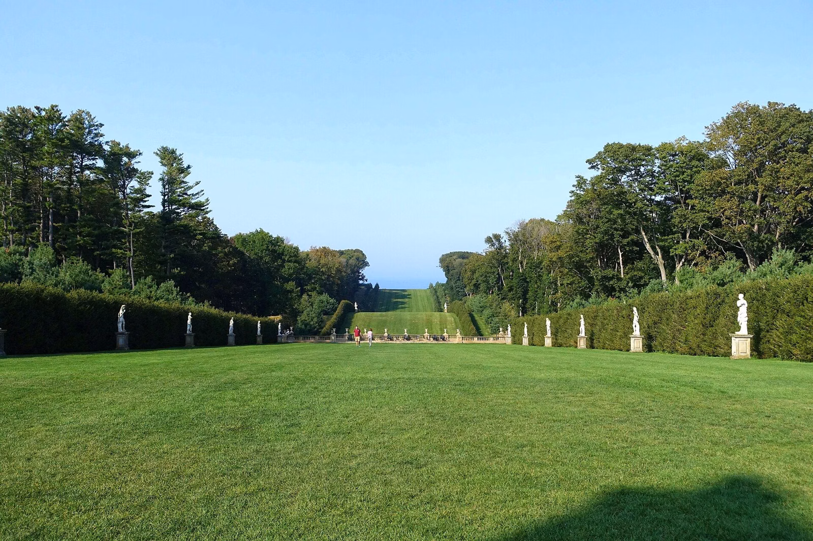 The Grand Allée at Castle Hill, lined with statues and hedges, with the ocean at the far end